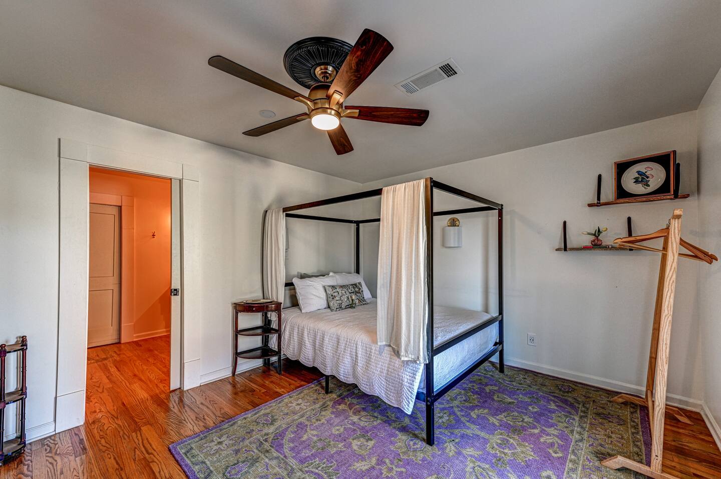 The Bower: bedroom with iron four-poster and purple rug