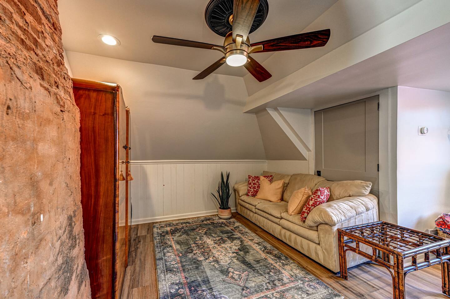 Attic lounge sitting area with couch and brick wall
